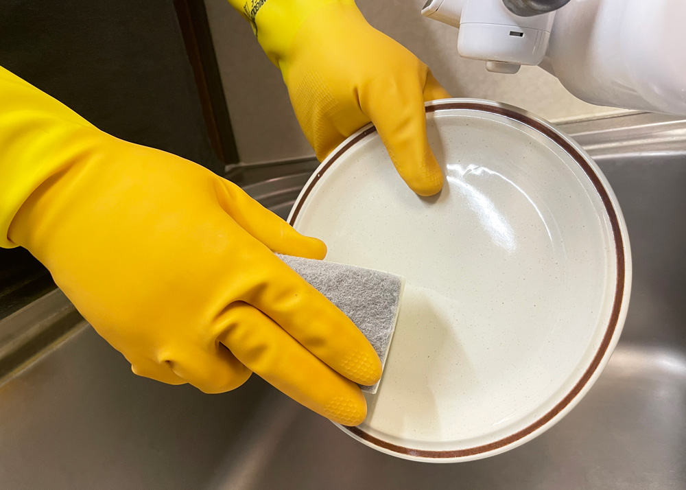 キッチン用グローブをつけて皿を洗う画像