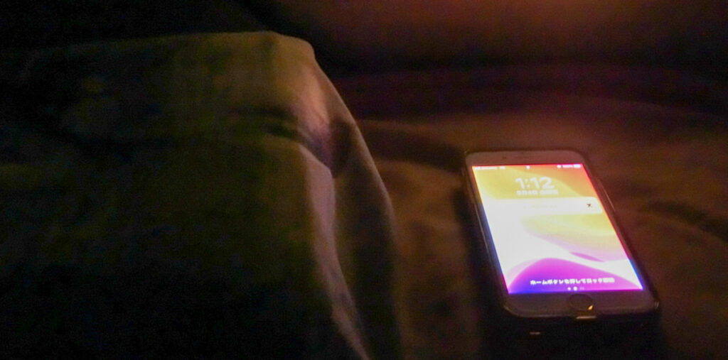 夜の枕元に置かれたスマホ